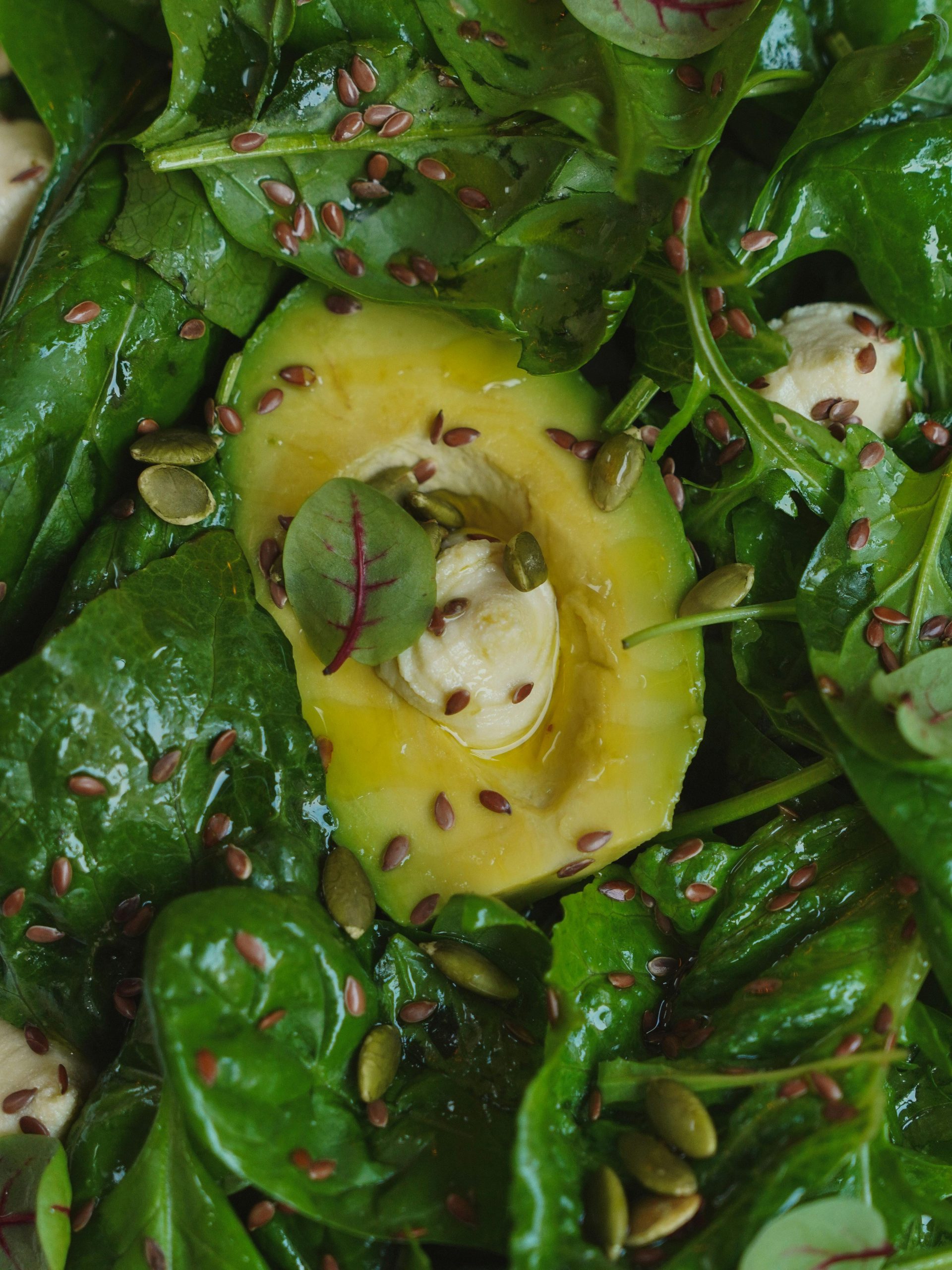 Groene salade met een halve avocado op een bedje van spinazie